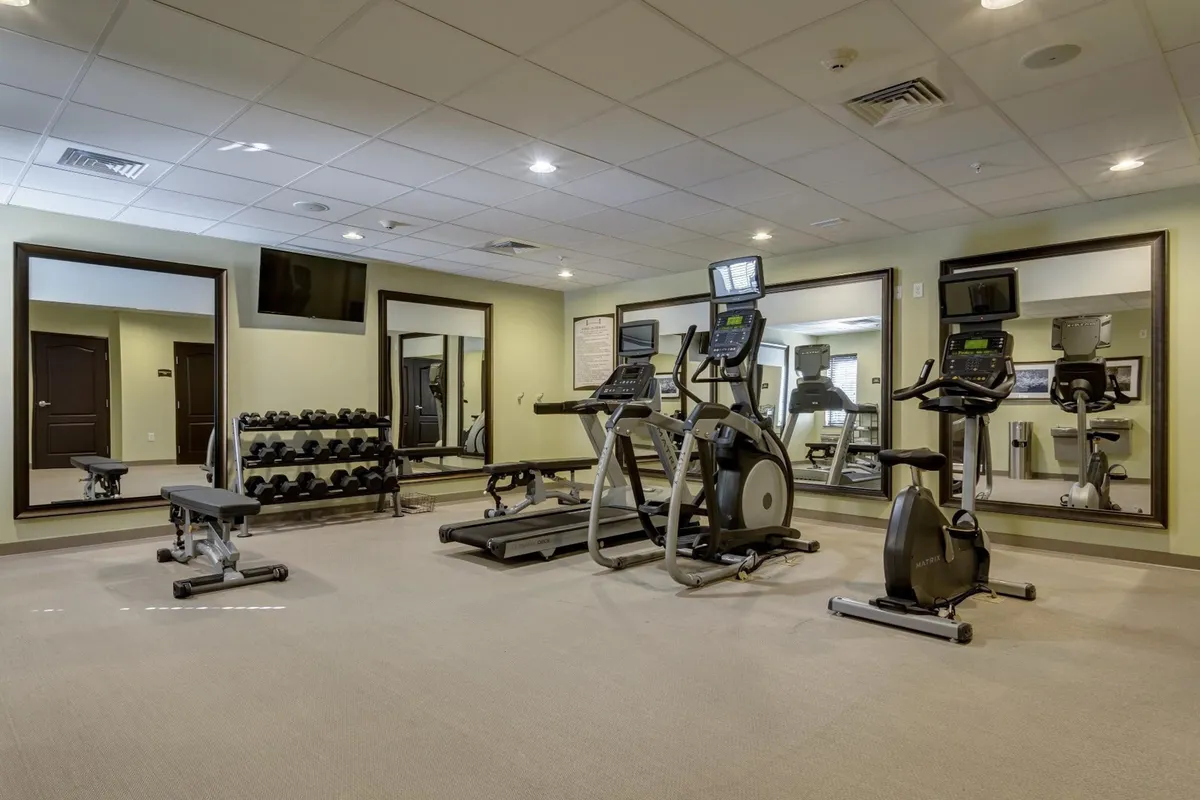 A motivational fitness center interior featuring modern exercise equipment such as dumbbells, cardio machines, and mirrors. The inviting setup suggests a dynamic environment ideal for both solo workouts and group classes.