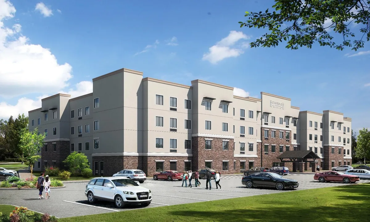 The exterior image features the hotel's entrance canopy, a landscaped area, the visible parking lot, and the building's facade. Guests can be seen parking vehicles and walking to the entrance, highlighting accessible parking and the welcoming first impression upon arrival.
