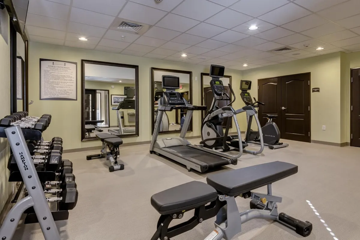 A bright, motivational fitness center featuring treadmills, ellipticals, free weights, and a weight bench. The space is designed for both cardio and strength training, creating an energetic and supportive environment for guests to recharge after a busy day.