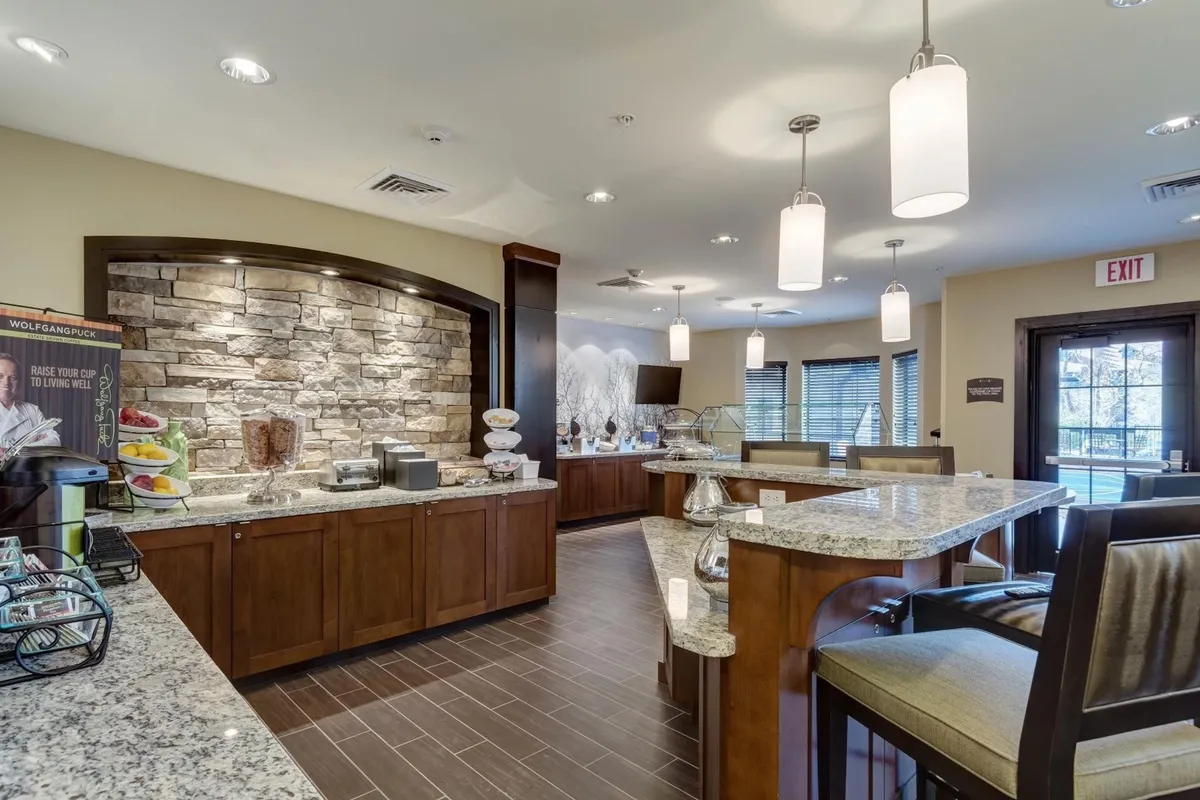 This image showcases a granite countertop with a stone wall backdrop, a cozy seating area, and a beverage station set up for guests to enjoy breakfast or coffee. The inviting ambiance suggests a welcoming space where guests can start their day or enjoy a casual meal.